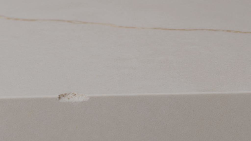 Close-up view of a damaged countertop edge showing a distinct chip before undergoing any repair or technical treatment.
