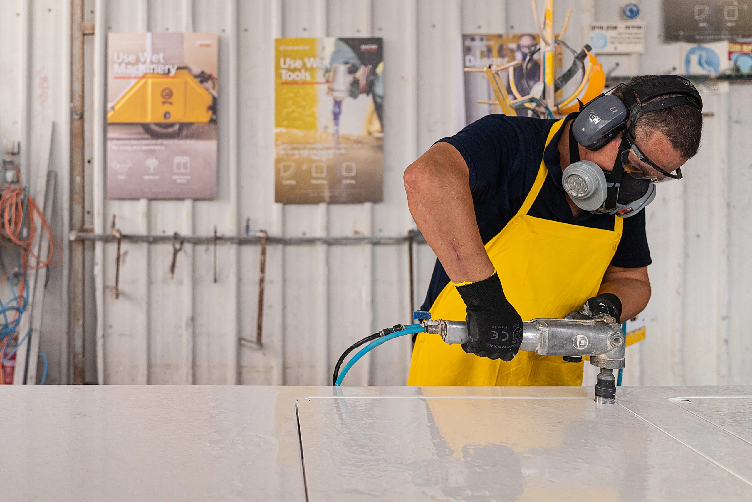 Fabrication & installation guide cover with Worker wearing protective gear and yellow apron uses power tool on a white surface.