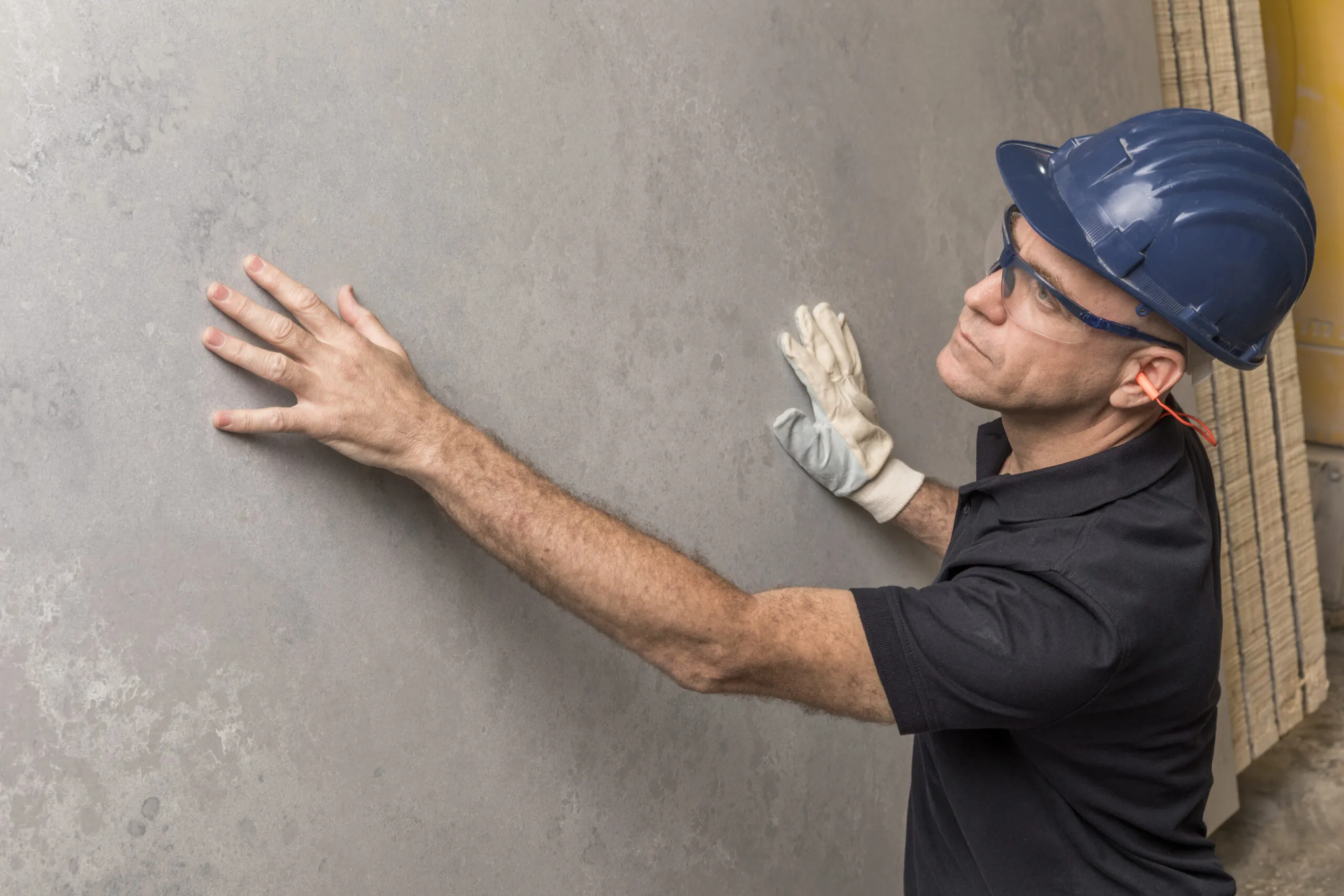 Man wearing a hard hat and gloves inspecting Caesarstone surface.