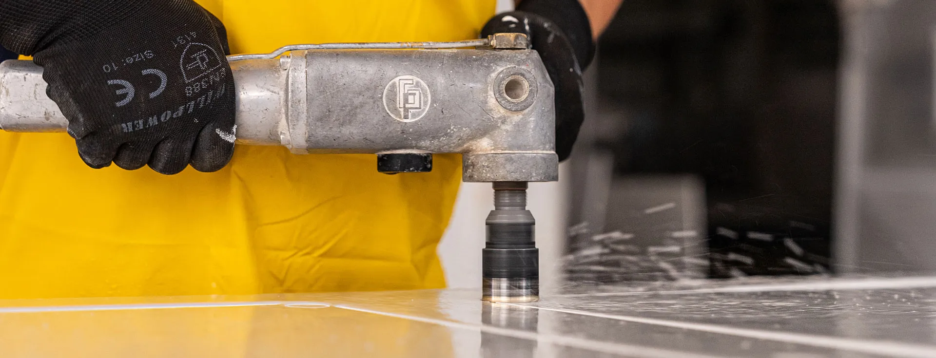 Fabrication & installation guide cover with Worker wearing protective gear and yellow apron uses power tool on a white surface.